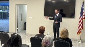 A man in a suit speaks to a small gathering of seated people
