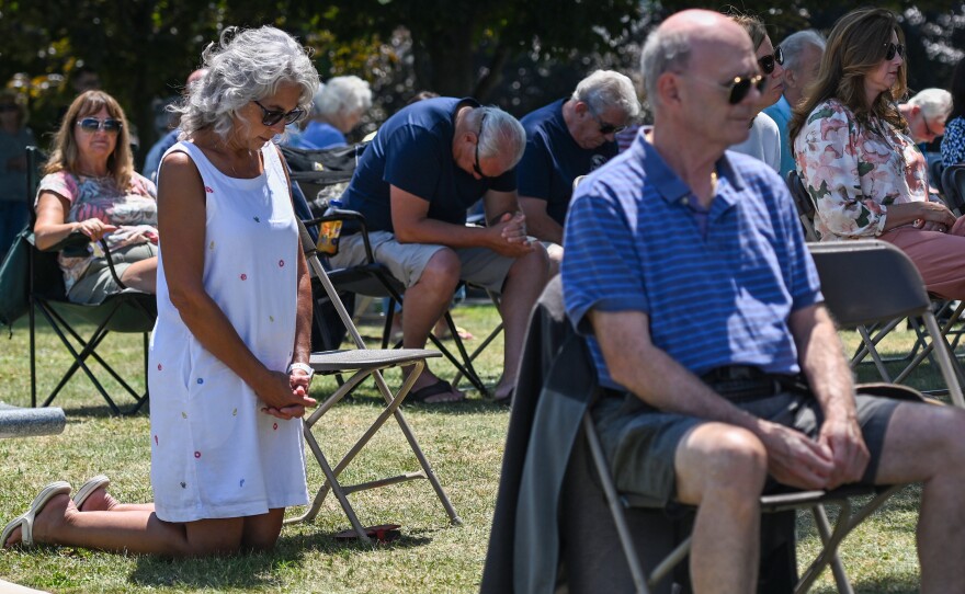 Donna Adrian a long time parishioner kneels in prayer during the Mass on Monday.