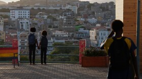 Two schoolgirls hold hands as they look towards the city in Praia, Cape Verde, Thursday, May 7, 2026. (AP Photo/Misper Apawu)