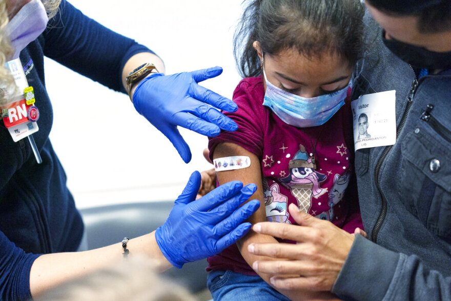 Kidney transplant patient Sophia Silvaamaya, 5, held by her father Pedro Silvaamaya, gets a bandage on her arm after getting vaccinated for COVID-19 by nurse Kelly Vanderwende, Wednesday, Nov. 3, 2021, at Children's National Hospital in Washington. The U.S. enters a new phase Wednesday in its COVID-19 vaccination campaign, with shots now available to millions of elementary-age children in what health officials hailed as a major breakthrough after more than 18 months of illness, hospitalizations, deaths and disrupted education.