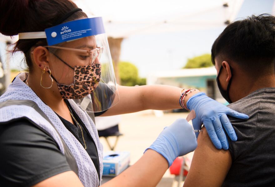 A 17-year-old receives a first dose of the Pfizer Covid-19 vaccine at a mobile vaccination clinic during a back to school event offering school supplies, Covid-19 vaccinations, face masks, and other resources for children and their families at the Weingart East Los Angeles YMCA in Los Angeles, California on August 7, 2021.