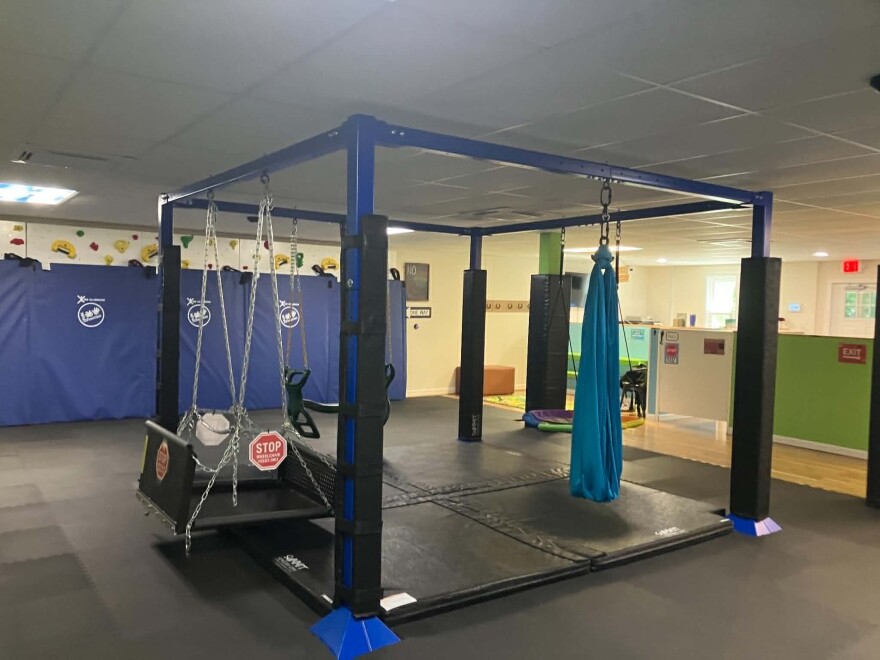 Several different types of indoor swings attached to metal beams with padding underneath.