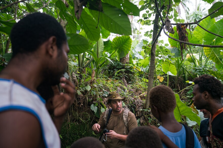 U.S. researcher Justin Taylan talks with residents who lead him to see World War II wreckage on a coconut plantation.