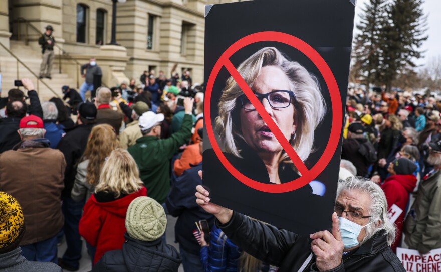 A man holds up a sign against Rep. Liz Cheney, R-Wyo., as Rep. Matt Gaetz, R-Fla., speaks to a crowd during a rally against her on Thursday in Cheyenne, Wyo.