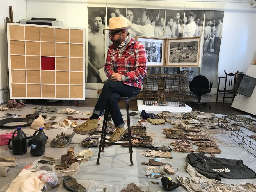 Israel Alejandro Garcia Garcia at his gallery, Garcia Squared Contemporary, surrounded by artifacts from his journey along the U.S. Meixco border.