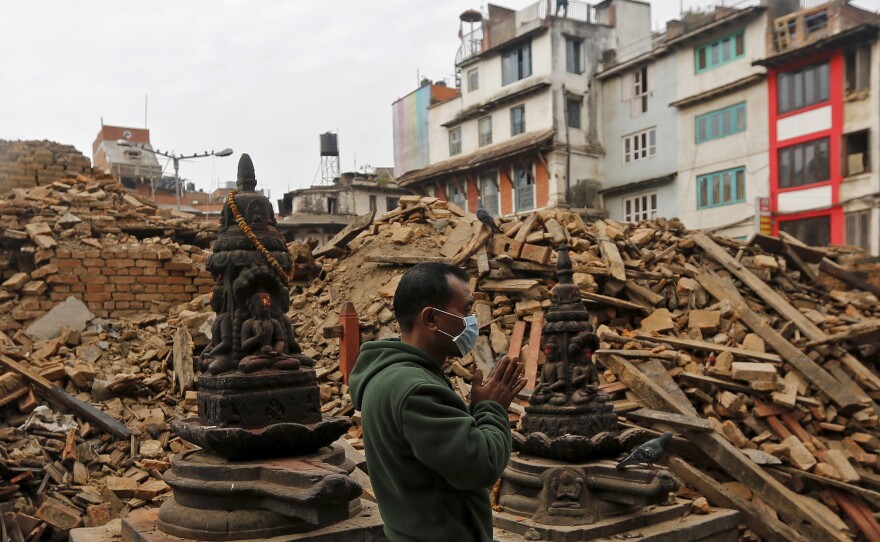 A man prays next to rubble of a temple destroyed in Saturday's earthquake in Kathmandu.