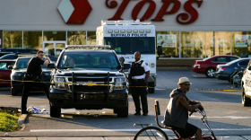 A cyclist pauses passes the scene of a shooting at a supermarket, in Buffalo, N.Y., Sunday, May 15, 2022.