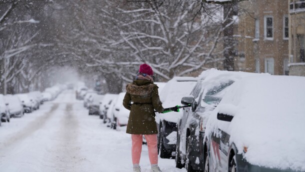 A person cleans the snow from a car during a snowy day in Chicago, Sunday, Jan. 25, 2026.