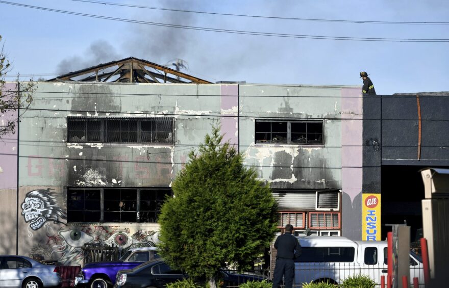 A firefighter walks on the roof of a smoldering building after a fire tore through a warehouse party early Saturday, Dec. 3, 2016 in Oakland. (Josh Edelson/AP)