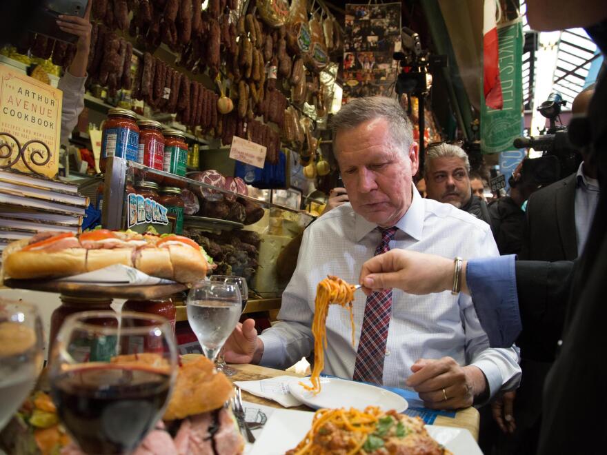 John Kasich watches spaghetti spooned onto his plate at Mike's Deli on Arthur Avenue in The Bronx, N.Y.