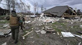 Members of the territorial defense forces walk in front of a destroyed house in Bohdanivka village, northeast of Kyiv. 