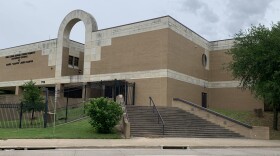 Tan brick building with stairs and trees to left and right