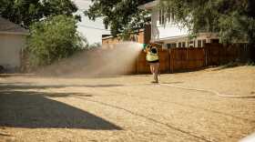 A worker waters a property in the Omaha Lead Superfund Site that's been remediated for high levels of lead in the soil.