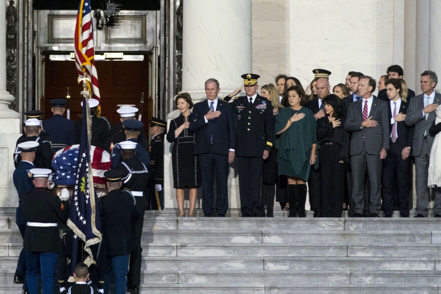 Former President George W. Bush, Laura Bush and other family members watch the flag-draped casket of former President George H.W. Bush on Monday, Dec. 3, 2018.