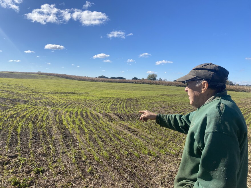 Manitowoc County farmer, Michael Slattery, is pictured in the right side of the photo wearing a green sweatshirt and black hat, as he points toward his field of crops.