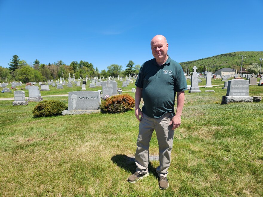 Renney Morneau, president of the Berlin Historical Society, stands in his family's burial plot among other French-Canadian names in Mount Calvary Cemetery.