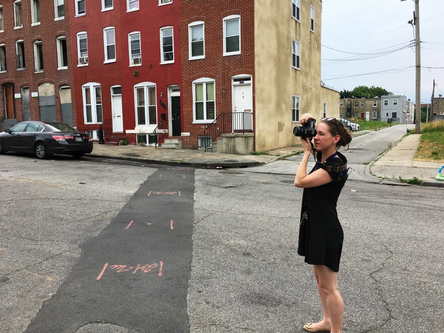 Baltimore-based artist Amy Berbert photographs a scene where someone was killed one year ago, as part of her series <em>Stains on the Sidewalk.</em>