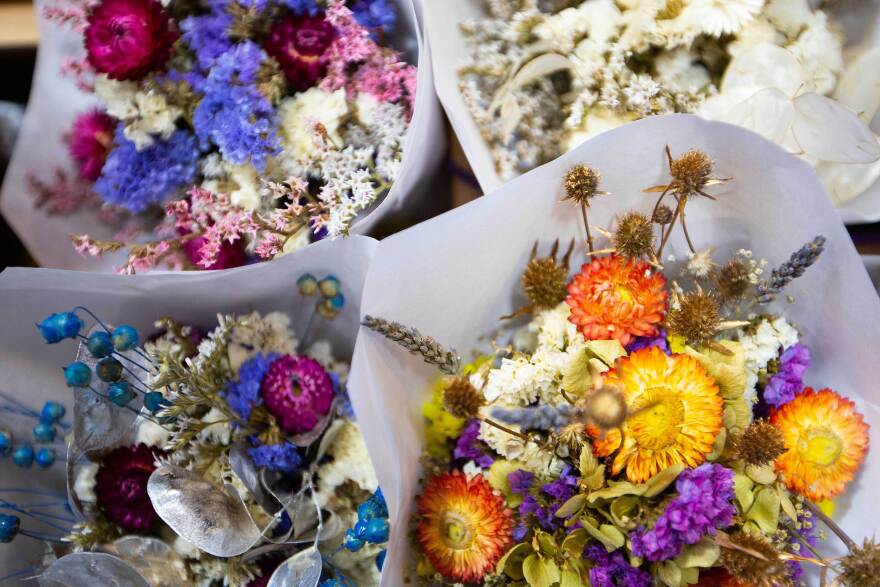 A close up of four bouquets of dried flowers some of which have purples and oranges, others blues and pinks.
