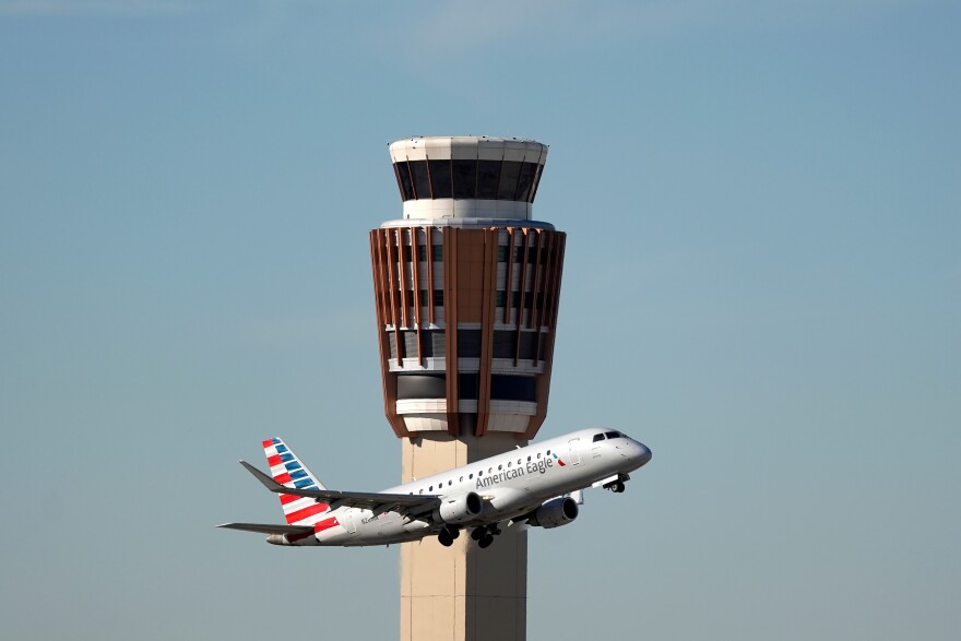 An airplane flies past the air traffic control tower 