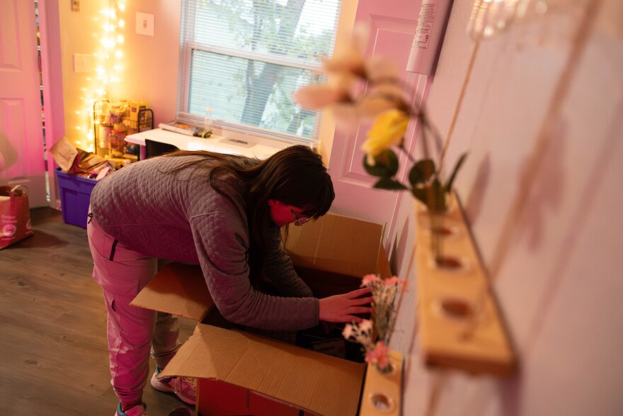 A person bends over a box in a pink room