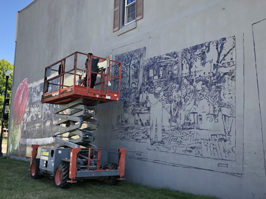 Walldogs artist Anat Ronen paints a mural featuring images of Washington's historic band stand on the side of a building on the city square. The Washington Historical Society hopes to bring a new mural to the square each summer leading up to Washington's bicentennial in 2025.