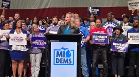 Michigan democratic gubernatorial candidate Jocelyn Benson stands in front of a podium with a Michigan Democrats sign on it. She is in front of a large crowd at the 2026 Michigan Democratic Convention. 