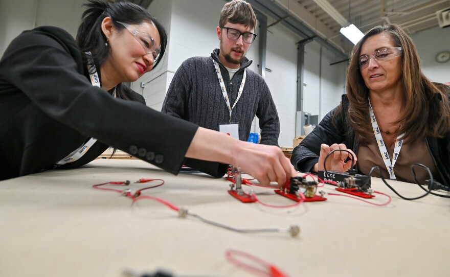 Christina Kloster, from Amazon, Dylan Housenick, an assistant professor at Luzerne County Community College, and Marybeth Williams, of the Pennsylvania Department Labor and Industry, learn about circuits that would be used in data centers during Amazon Web Services' Information Infrastructure Workshop for Educators at Luzerne County Community College.