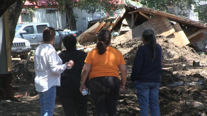 A family takes in the damage done in Tuesday's flood.