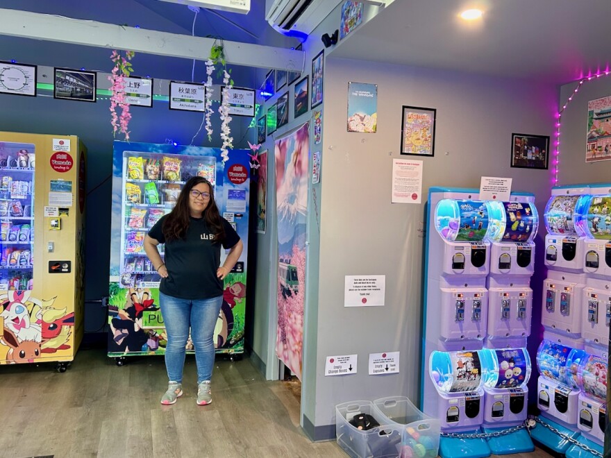 A woman stands in front of vending machines filled with Japanese food items.