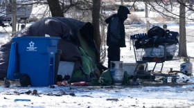 A homeless person checks a cart in front of a tent during a cold day in Chicago, Thursday, Jan. 22, 2026.