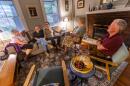 Pam McColl, Jacqui Comstock, her husband Holger Buchholz, Jacqui’s mother, Ruth Comstock, and Pam’s husband, Will McColl, have a conversation in the McColl’s living room in Roslindale. (Jesse Costa/WBUR)