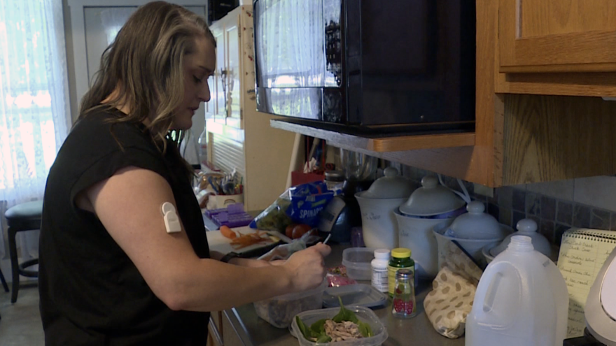 a woman stands in a kitchen preparing food.