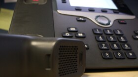 A black landline telephone on desk with receiver off