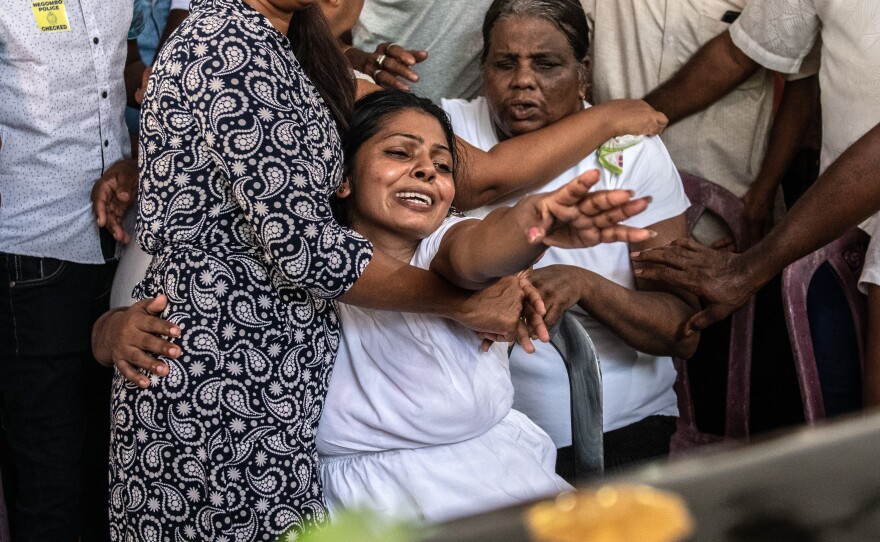 A woman cries as she reaches toward a coffin in Negombo. More than 300 people were killed in the attacks.