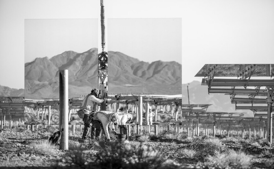 Workers install a "heliostat" — or a device with a mirror that reflects the sun, or in this case the nearby mountains. Background shows assembled heliostats in "safe" or resting position. June 2012.