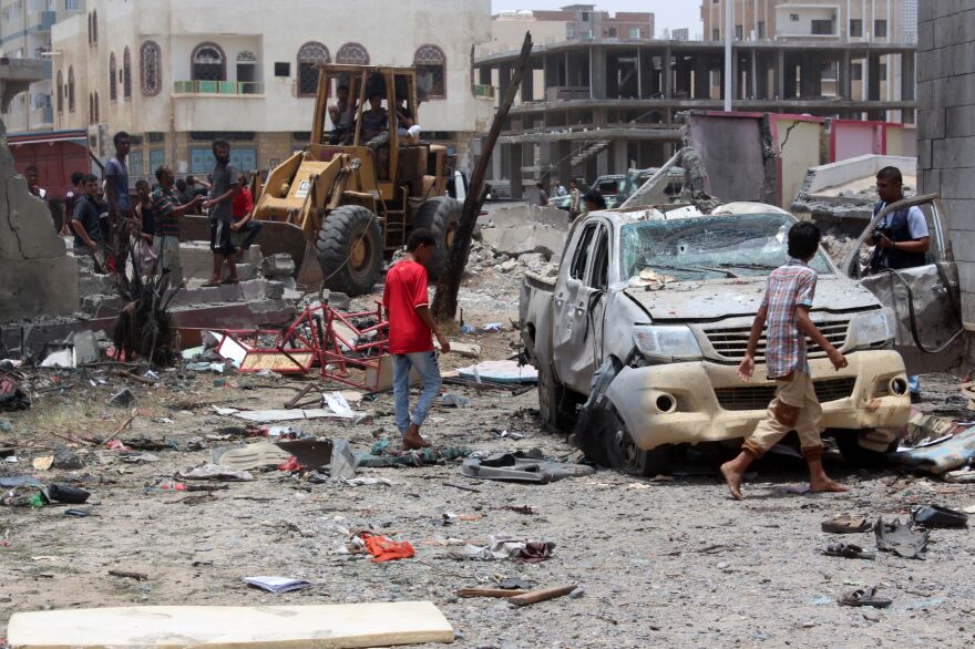 Yemenis inspect the site of a suicide car bombing at an army recruitment center in Aden, Yemen, on Monday.