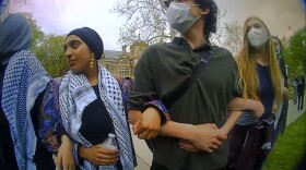 A screen capture from a police officer’s body camera footage shows four young people standing outside with their arms linked. 