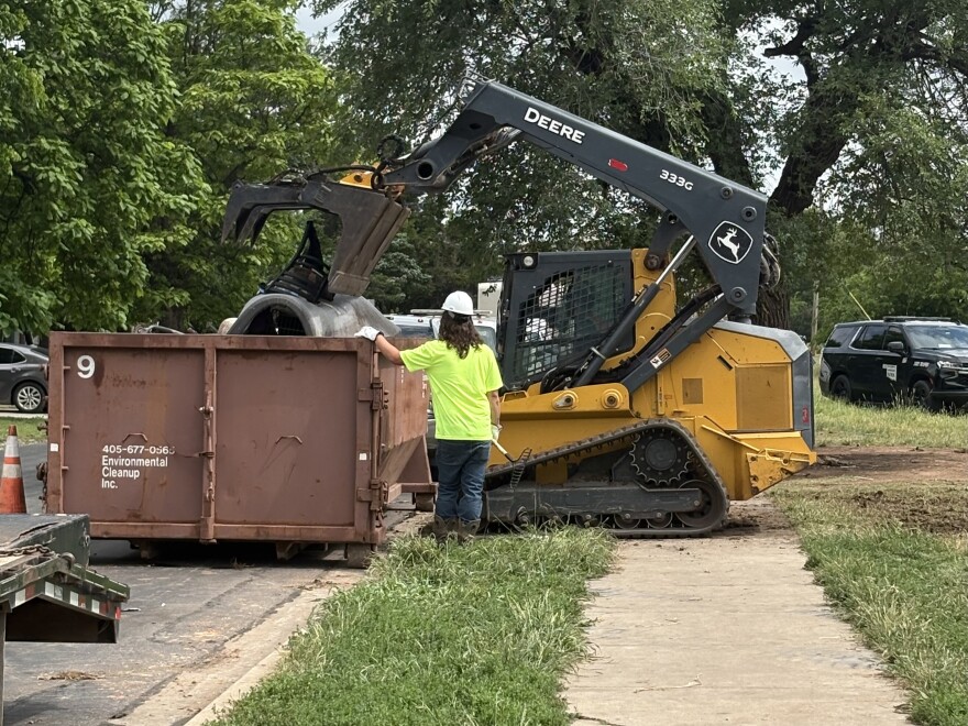 A cleanup crew throws away bedding and furniture during an Operation SAFE encampment sweep in Norman on Friday, May 22.