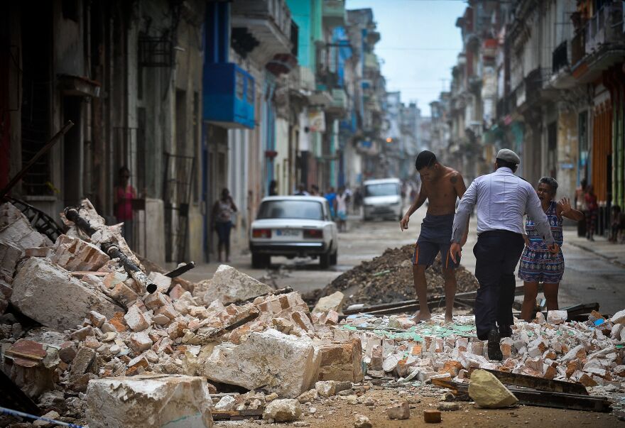 Cubans wade through the rubble from a collapsed building in Havana, on Saturday. The Cuban government extended its maximum state of alert to three additional provinces, including Havana, amid fears of flooding in low-lying areas.