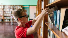 A student picks out a book at a library.