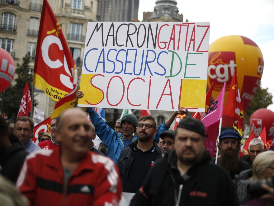 Protesters hold a banner saying, "Macron and Gattaz, breakers of the social safety net," which refers to President Macron and Pierre Gattaz, leader of a French business association.