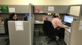 Two workers sit in side-by-side cubicles operating phone lines at the Hillsborough County Social Services office.