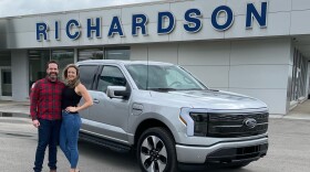 Nick Schmidt poses with his wife after picking up his brand new electric F-150. Schmidt was the first buyer to get the F-150 Lightning as auto makers are betting billions in an electric future.