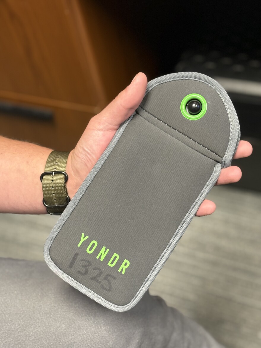 Assistant Principal Dave DeRose shows how Yonder pouches work. Students at Summit High School are required to stow their devices in these lockable sleeves during the school day.