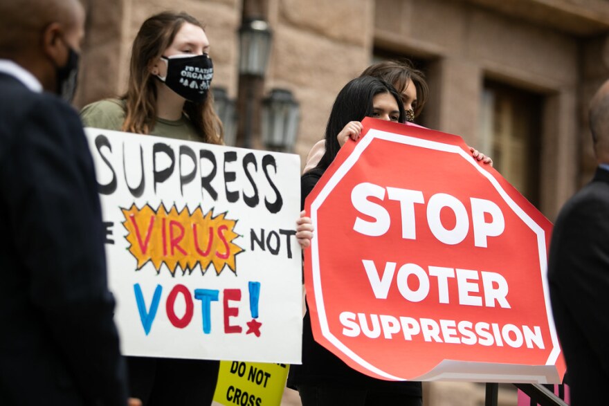 People hold signs in opposition to GOP voting legislation, outside of the state Capitol on April 21.
