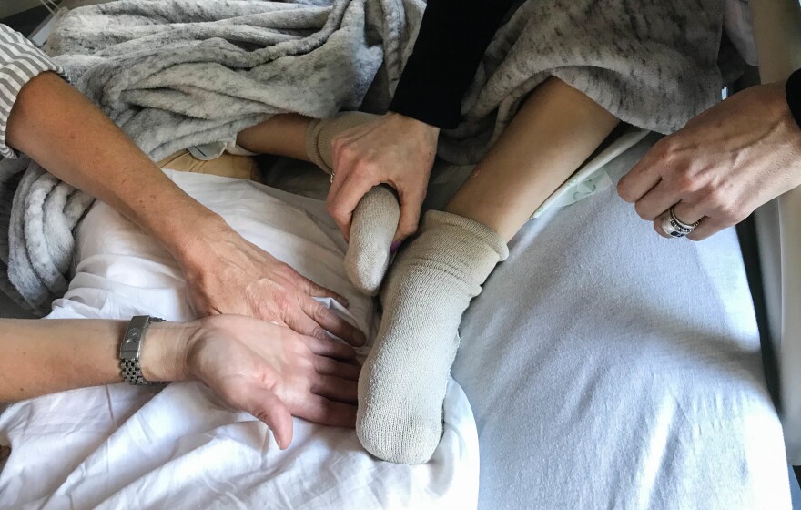 Robyn Adcock (left), a University of California, San Francisco pain relief specialist, gently guides Jessica Greenfield to acupressure points on her son's foot and leg that have helped relieve his chronic pain.