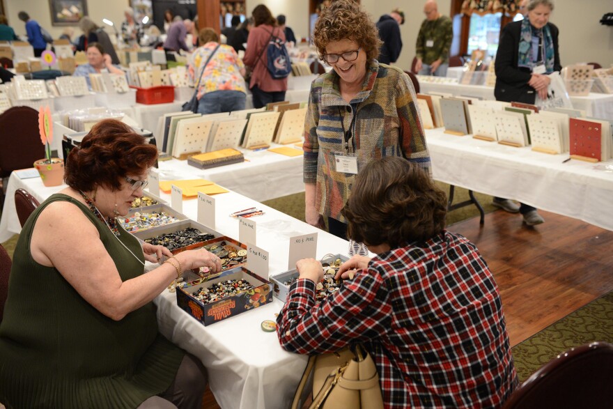 A group of women look through boxes of buttons