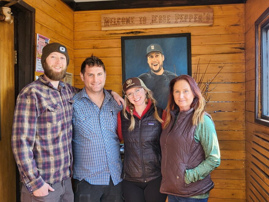In the entrance vestibule of Jesse Pepper’s Smoke Shack, from left to right, Oliver Redding, Travis Kathan, Lilli Redding and Melody Redding stand in front of the painting, gifted to them by daughter and sister Bailey, of Jesse Redding.