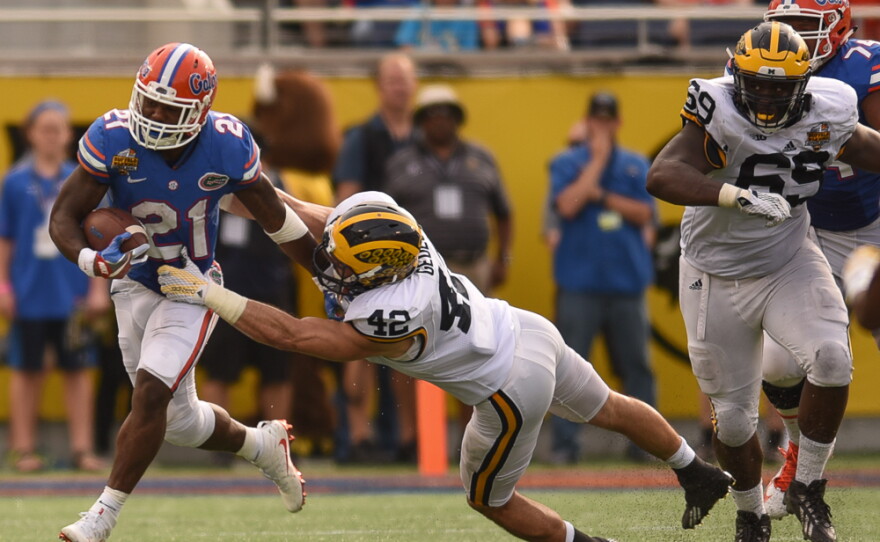 Florida running back Kelvin Taylor (21) stiffarms Michigan linebacker Ben Gedeon (42) as he turns the corner and heads upfield. (Greenberry Taylor/WUFT News)