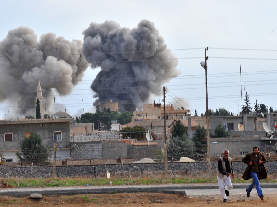 A picture taken from the adjacent Turkish border town of Ceylanpinar shows people running in front of smoke after a Syrian aircraft bombed the strategic border town of Ras al-Ain earlier today.